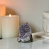 Amethyst crystal on a marble surface with a candle in the background