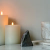 Candle and amethyst cut base stone on a surface with a blurred background