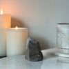 Decorative stone sculpture on a marble surface with candles in the background