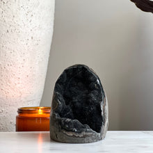  Black Amethyst crystal on marble stand with candle and plant in the background