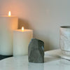 Candle and decorative black amethyst cut base stone on a marble surface with a neutral background