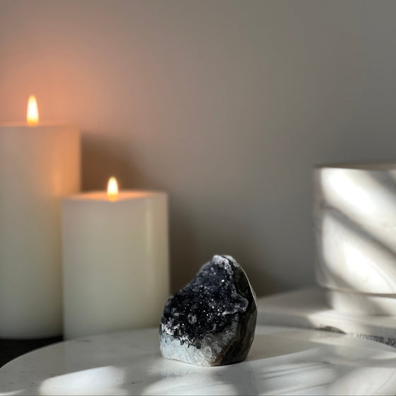 Candlelit scene with a crystal on a surface against a neutral background