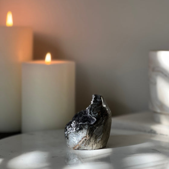 Decorative crystal on a marble surface with candles in the background