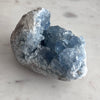 Celestite Mineral specimen with blue crystal formation on a light gray background