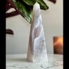 Druzy Agate Tower placed on marble stand with plant and candle in the background.