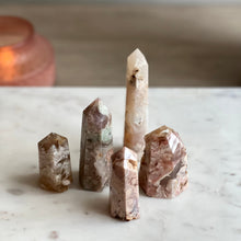  Flower Agate Points on marble stand with candle in background.