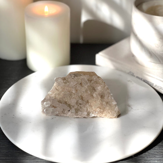 Himalayan Quartz on a white marble stand with candles and book in the background