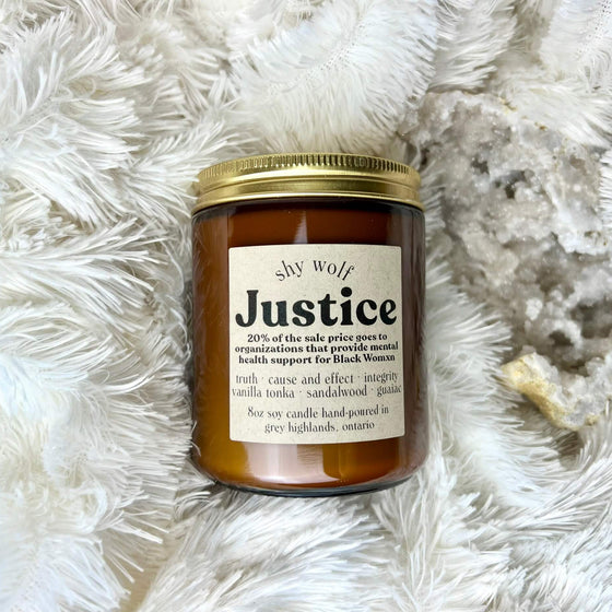 A brown glass jar with a label that reads 'Justice' on a white furry surface.