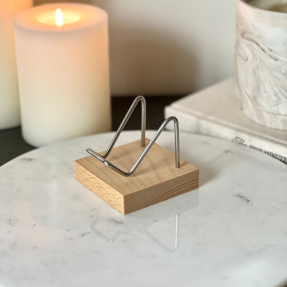 A large wood and silver crystal stand displayed on a marble pedestal with candles and a book in the background.