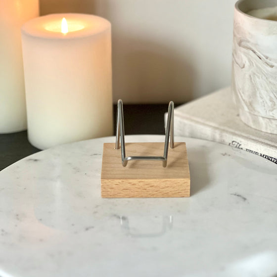 A Large wood and silver crystal stand displayed on a marble pedestal with candles and a book in the background.