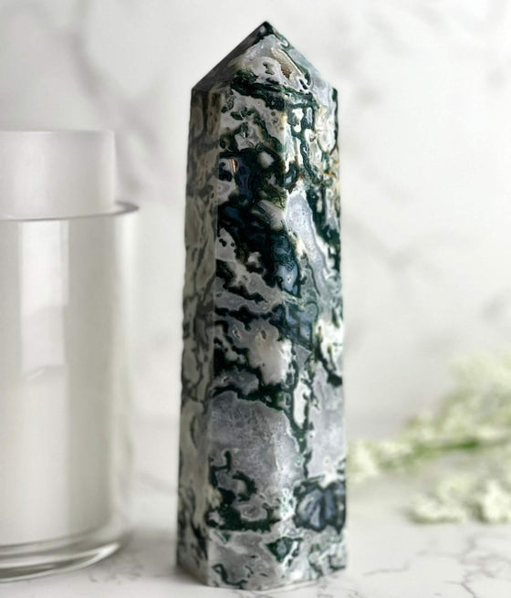 Moss Agate Tower with candle and flowers in the background.