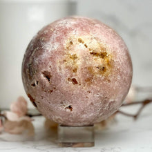  Pink Amethyst Sphere on stand with flowers and candle in the background.