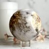Pink Amethyst marble-like sphere on a stand with a blurred background