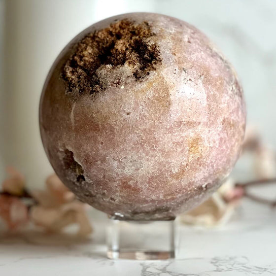 Pink Amethyst Sphere sphere on stand featuring a blurred background.