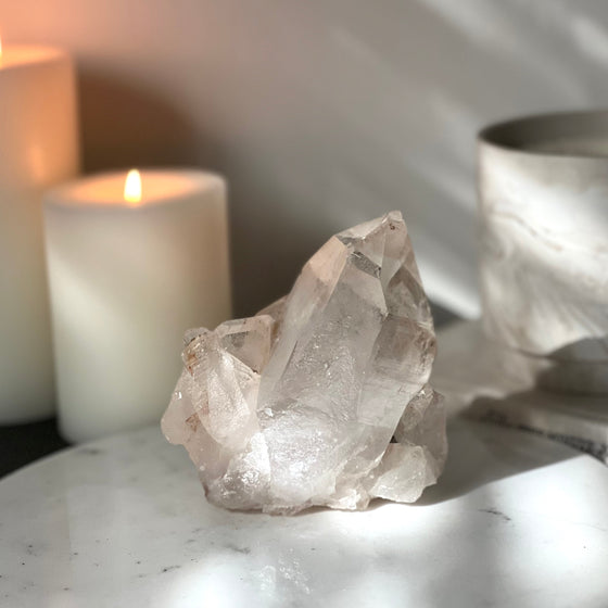 Crystal on a marble surface with candles and a metallic container in the background