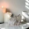 Pink Himalayan Samadhi Quartz on a marble stand with candles and a book in the background.
