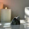 Mineral specimen on a reflective surface with a blurred candle in the background