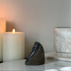 Gray black rainbow amethyst, white candle, and decorative pot on a surface with a neutral background