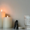 Decorative dark gray crystal on a marble surface with a lit candle in the background