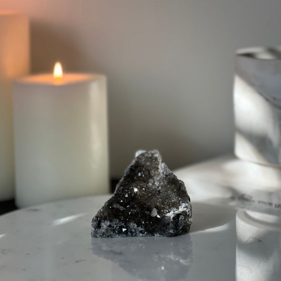 Crystal rock on a marble surface with a candle in the background
