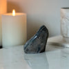 A side view of a natural rainbow amethyst stone featured on a white marble platform. 