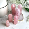 Rose Quartz Points with blurred background featuring a candle and flowers.