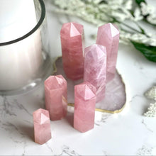  Rose Quartz Points with blurred background featuring a candle and flowers.
