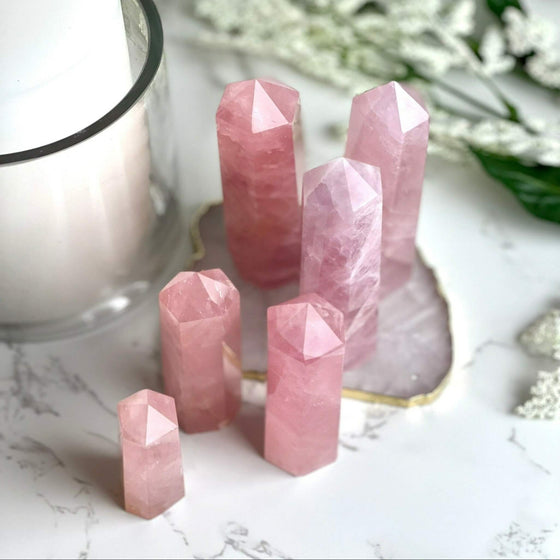 Rose Quartz Points with blurred background featuring a candle and flowers.