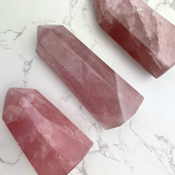 Three pink crystal points on a white marble surface