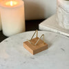 Small wood and gold crystal stand displayed on a marble pedestal with candles and a book in the background.