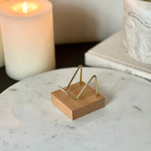  Small wood and gold crystal stand displayed on a marble pedestal with candles and a book in the background.