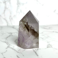  A smoky amethyst point crystal on a marble surface.