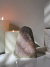 Decorative Rainbow Amethyst crystal on a reflective surface with candles in the background video.