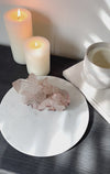 Pink Himalayan Quartz Cluster on white stand with book and candles.
