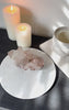 Pink Himalayan Quartz Cluster on white stand with book and candles.